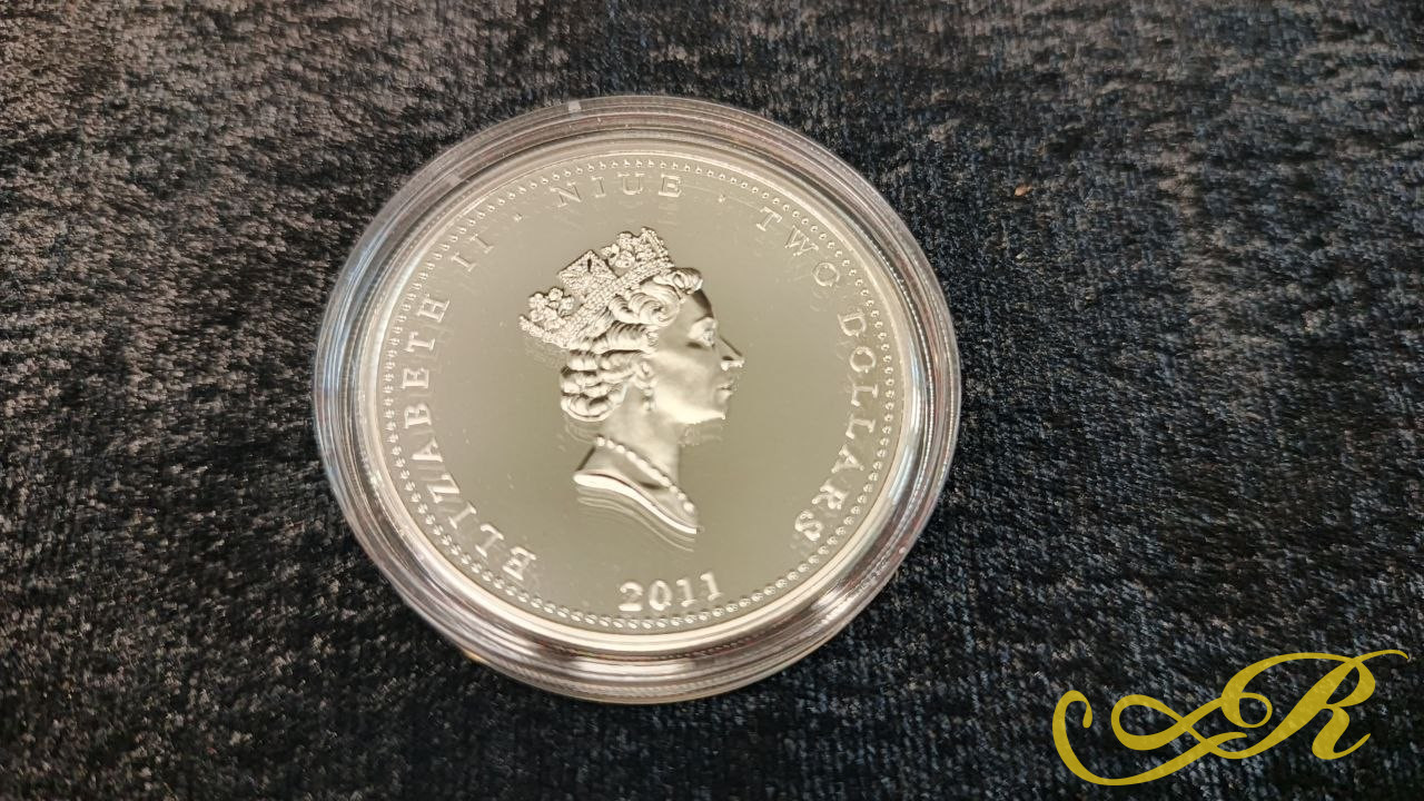 Памятная серебряная монета номиналом 2 новозеландских доллара (остров Ниуэ) 2011 года выпуска. На аверсе отчеканен профиль королевы Великобритании Елизаветы II, указана страна-эмитент «NIUE», номинал «TWO DOLLARS» и год «2011». Серебро 999
